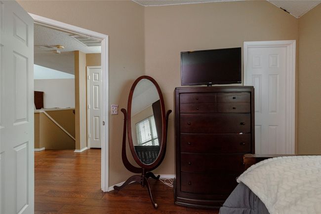 Bedroom with a textured ceiling, baseboards, vaulted ceiling, and dark wood finished floors | Image 28