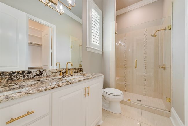 Bathroom with a shower stall, crown molding, tile patterned floors, vanity, and toilet | Image 20