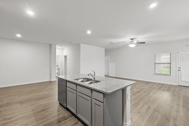 Kitchen featuring gray cabinets, dishwasher, open floor plan, a ceiling fan, and an island with sink | Image 13