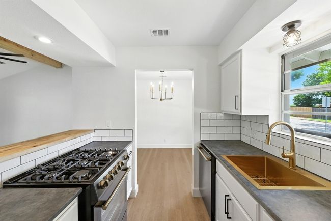 Kitchen with stainless steel appliances, dark countertops, light wood finished floors, backsplash, and recessed lighting | Image 12
