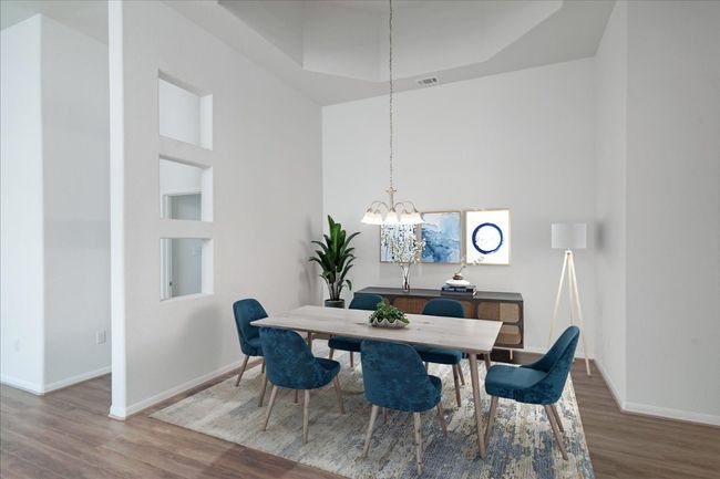 Dining room with wood finished floors, baseboards, a chandelier, a towering ceiling, and a tray ceiling | Image 16
