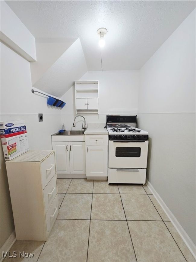 Kitchen with range, open shelves, white cabinetry, light countertops, and a textured ceiling | Image 20