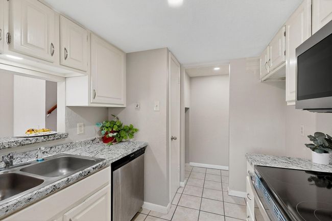 Kitchen featuring stainless steel appliances, light tile patterned floors, light countertops, and white cabinets | Image 6