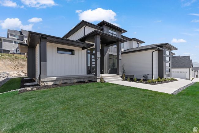 View of front of property featuring a garage, a front yard, and board and batten siding | Image 5