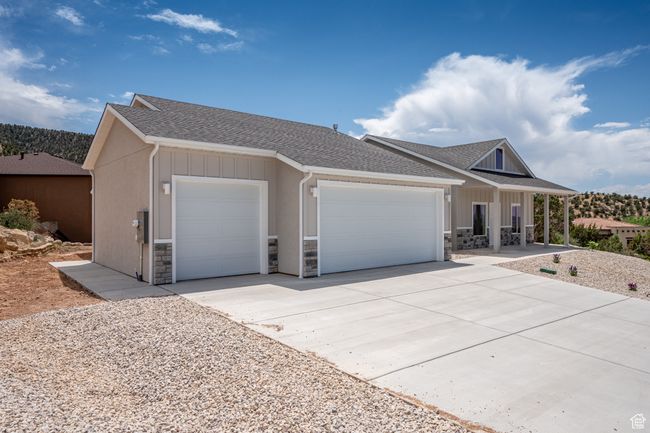 View of front of house with a garage, stone siding, roof with shingles, and a porch | Image 6