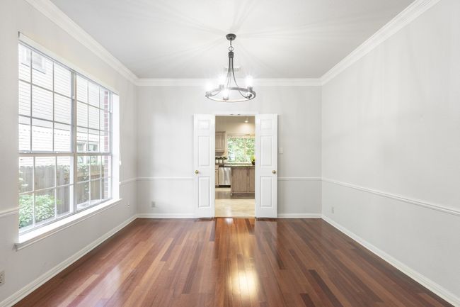 Unfurnished dining area featuring dark wood finished floors, baseboards, crown molding, and a chandelier | Image 21