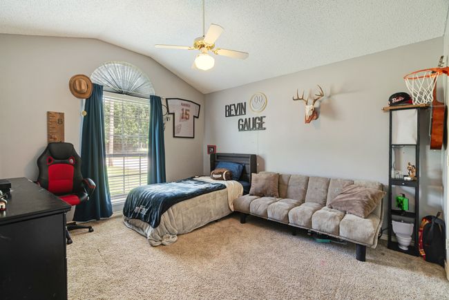 Carpeted bedroom with vaulted ceiling, a ceiling fan, and a textured ceiling | Image 15