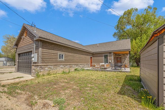 Back of house featuring stone siding, a yard, and concrete driveway | Image 5