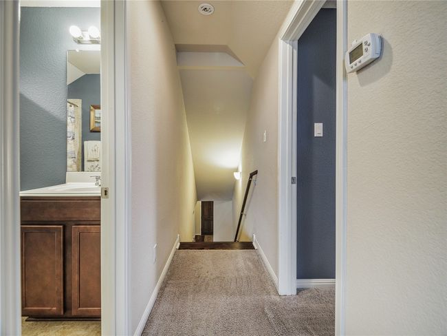 Hallway featuring an upstairs landing, vaulted ceiling, light colored carpet, a sink, and baseboards | Image 32