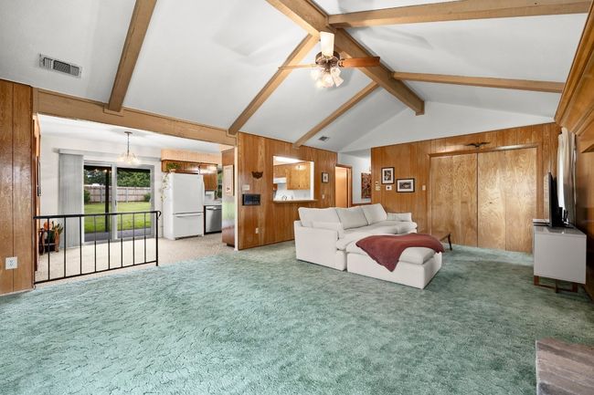 Living room with wood walls, light carpet, and a ceiling fan | Image 7