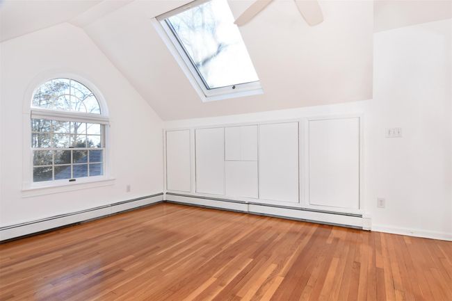 Upstairs bedroom with vaulted ceiling with skylight, baseboard heating, and light wood finished floors | Image 15