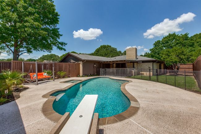 View of swimming pool featuring a fenced backyard, a patio, a diving board, and an in-ground hot tub | Image 33
