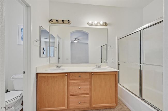 Bathroom featuring ceiling fan, toilet, double vanity, and shower / bath combination with glass door | Image 17