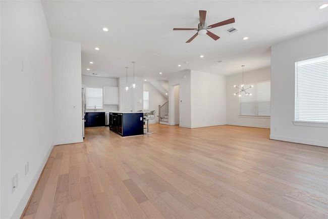 A different view for the family room, you can see the kitchen, dining space and a wooden staircase leading up stair. | Image 8