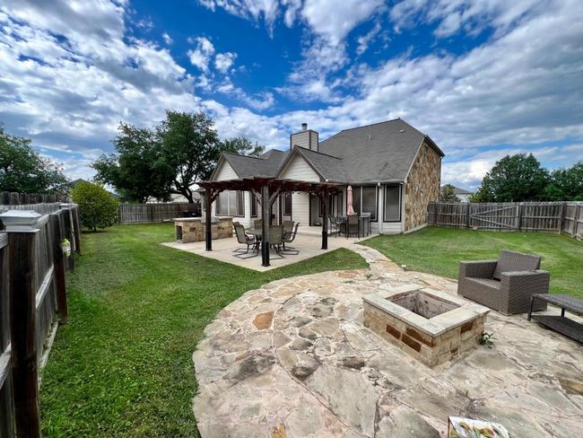 Rear view of property featuring a fire pit, a chimney, a patio, and a fenced backyard | Image 16