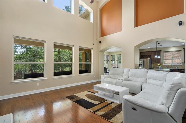 Living room with baseboards, dark wood-style flooring, arched walkways, a high ceiling, and a ceiling fan | Image 10