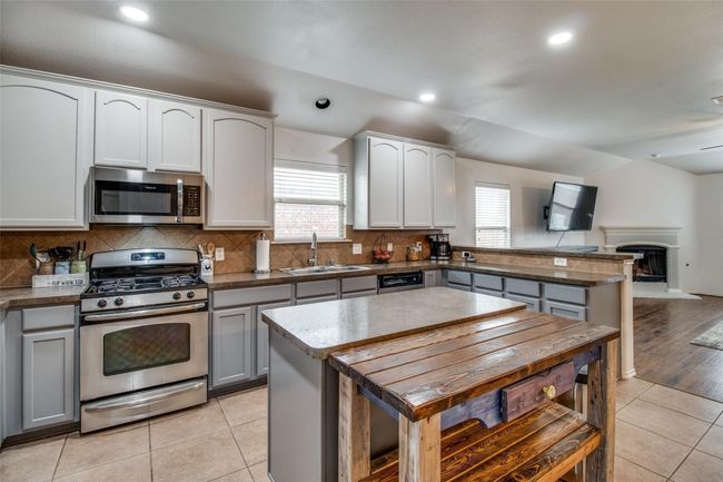 Kitchen featuring stainless steel appliances, a sink, a peninsula, healthy amount of natural light, and lofted ceiling | Image 8