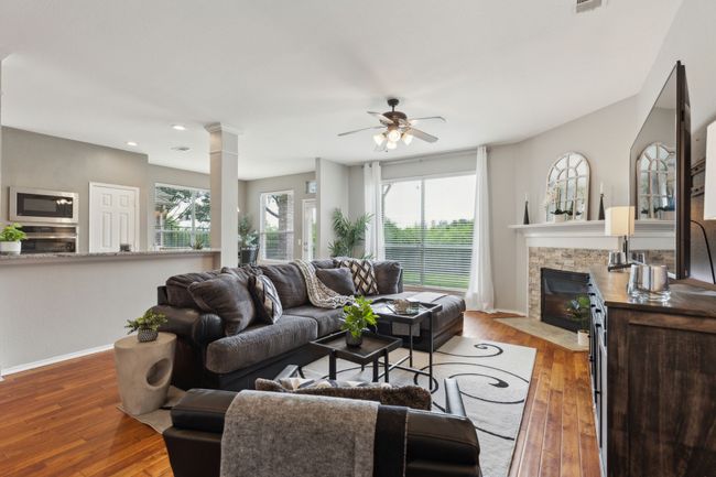 Living room with baseboards, a fireplace with flush hearth, ceiling fan, wood-type flooring, and plenty of natural light | Image 14