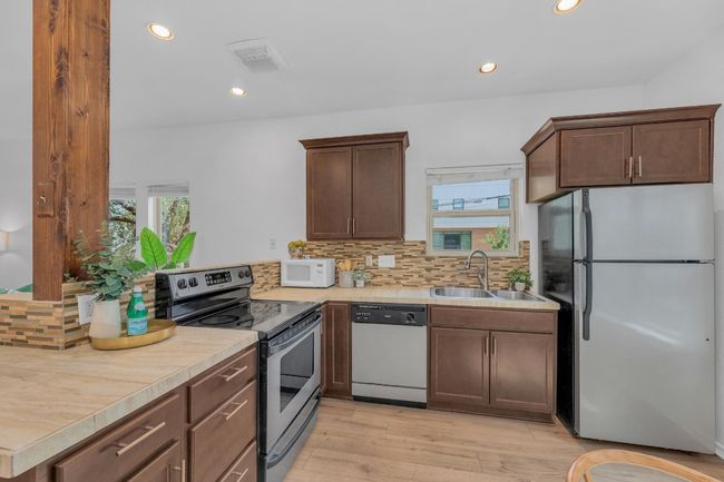 Kitchen with appliances with stainless steel finishes, backsplash, light wood-style floors, recessed lighting, and light countertops | Image 14