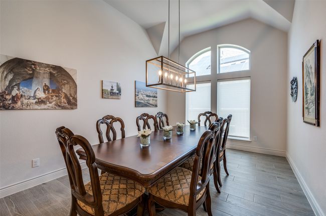 Dining space with a chandelier, wood finished floors, lofted ceiling, and baseboards | Image 7