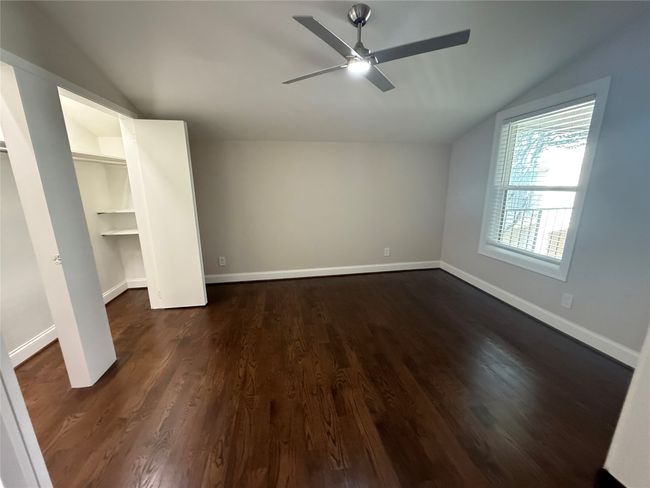 Unfurnished bedroom with vaulted ceiling, baseboards, dark wood finished floors, and a ceiling fan | Image 14