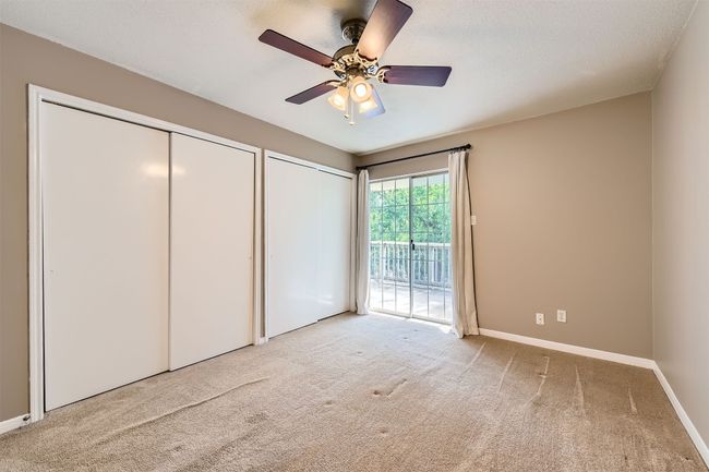 Bedroom featuring access to outside balcony, two closets, carpet, and ceiling fan. | Image 10