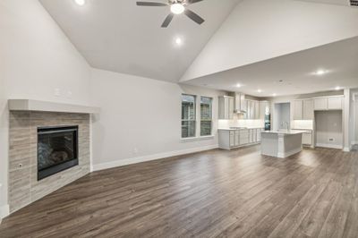 Unfurnished living room featuring high vaulted ceiling, wood-type flooring, a tile fireplace, and ceiling fan | Image 3