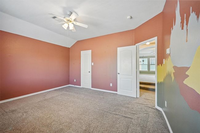 Unfurnished bedroom featuring carpet floors, baseboards, lofted ceiling, and a ceiling fan | Image 29