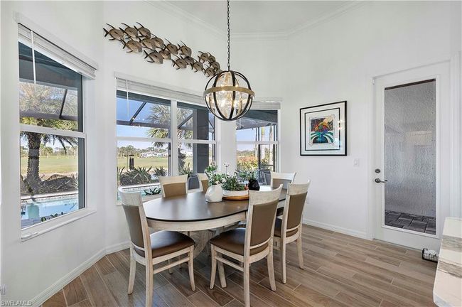 Dining room with light wood finished floors, baseboards, crown molding, and an inviting chandelier | Image 38
