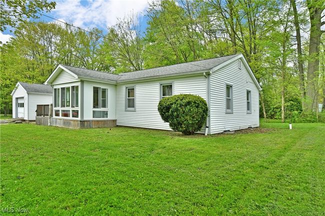 Back of property featuring a sunroom, a lawn, and roof with shingles | Image 43