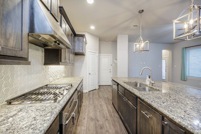 Kitchen with under cabinet range hood, a chandelier, stainless steel appliances, dark brown cabinetry, and recessed lighting | Image 21