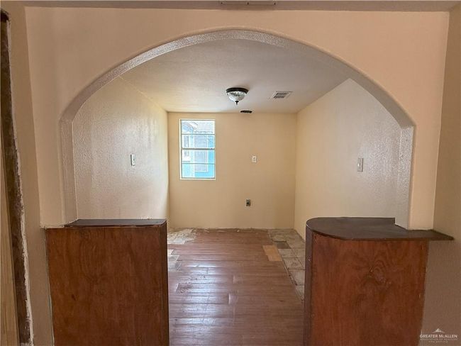Empty room featuring visible vents, arched walkways, a textured wall, and hardwood / wood-style floors | Image 17