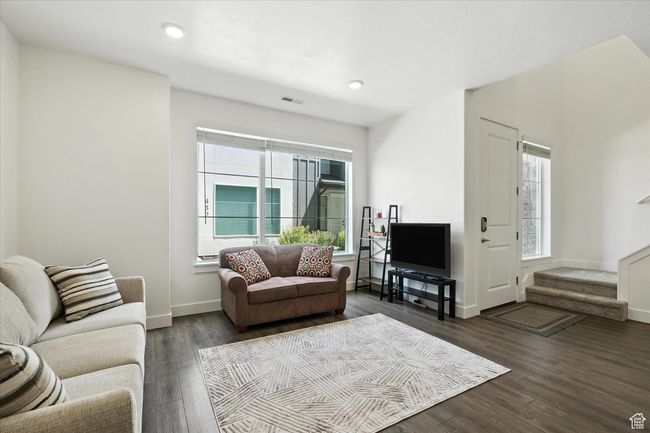 Living area featuring plenty of natural light, dark wood-style flooring, stairway, and recessed lighting | Image 6
