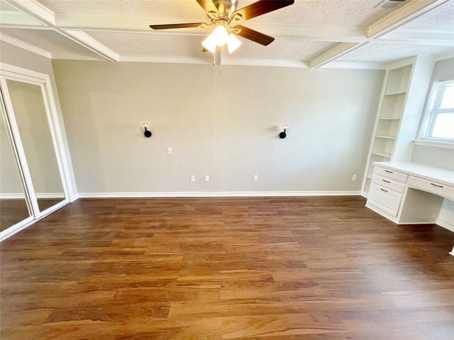 Unfurnished room featuring beam ceiling, built in shelves, coffered ceiling, wood finished floors, and ornamental molding | Image 18