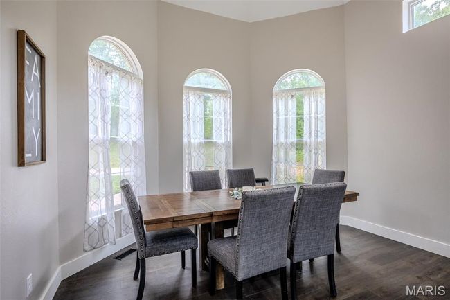 Dining room featuring plenty of natural light, dark wood-type flooring, and a towering ceiling | Image 9