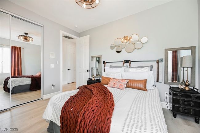 Bedroom featuring a closet, visible vents, light wood finished floors, baseboards, and a notable chandelier | Image 43