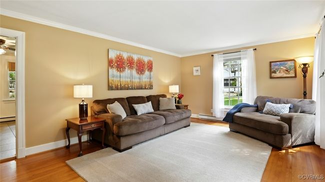 Living room with ornamental molding, wood finished floors, a baseboard radiator, and ceiling fan | Image 50