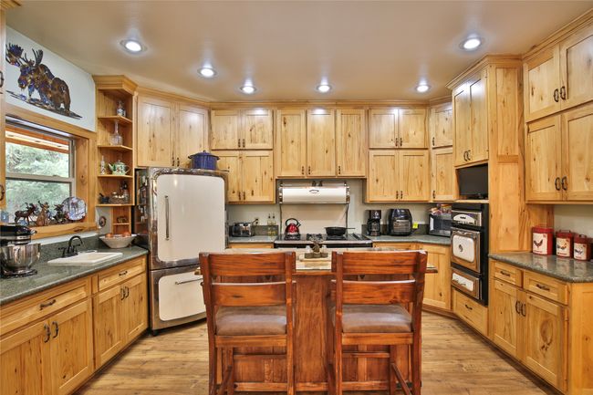 Kitchen with under cabinet range hood, open shelves, a sink, freestanding refrigerator, and light wood-style floors | Image 10
