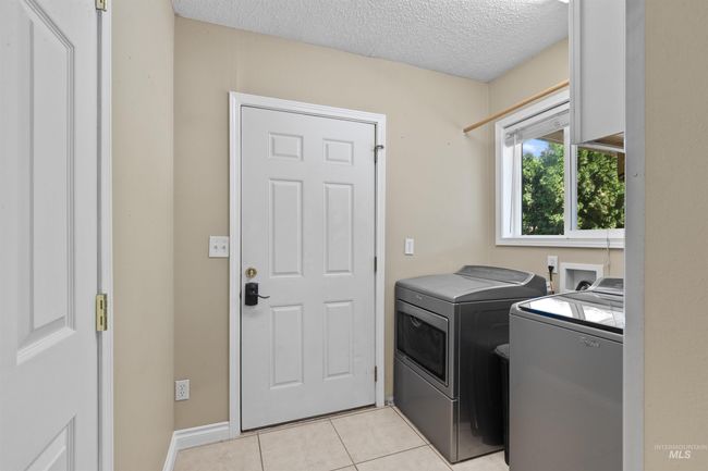 Laundry room with independent washer and dryer, a textured ceiling, and light tile patterned floors | Image 22