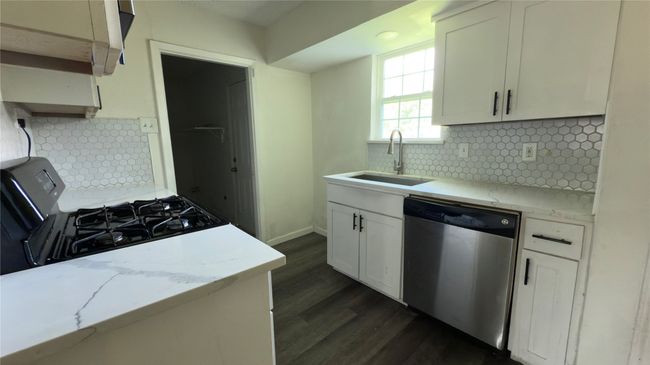 Kitchen featuring tasteful backsplash, dishwasher, white cabinetry, dark wood-type flooring, and gas stove | Image 5