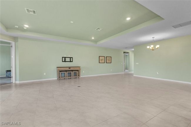 Unfurnished living/dining room featuring a chandelier, visible vents, and a raised ceiling | Image 22