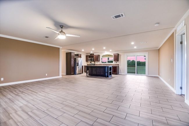 Unfurnished living room with crown molding, baseboards, a ceiling fan, and recessed lighting | Image 6
