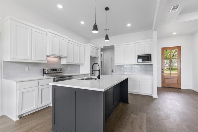 Kitchen featuring visible vents, built in microwave, dark wood finished floors, stainless steel electric range, and a sink | Image 15