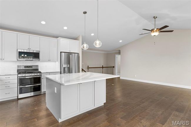 Kitchen with appliances with stainless steel finishes, lofted ceiling, a center island, a ceiling fan, and open floor plan | Image 9