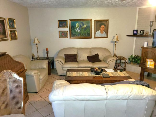 This cozy living room features neutral-toned walls and tiled flooring | Image 4
