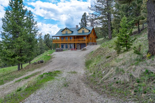 View of front of house featuring dirt driveway, stone siding, a deck, and a chimney | Image 61