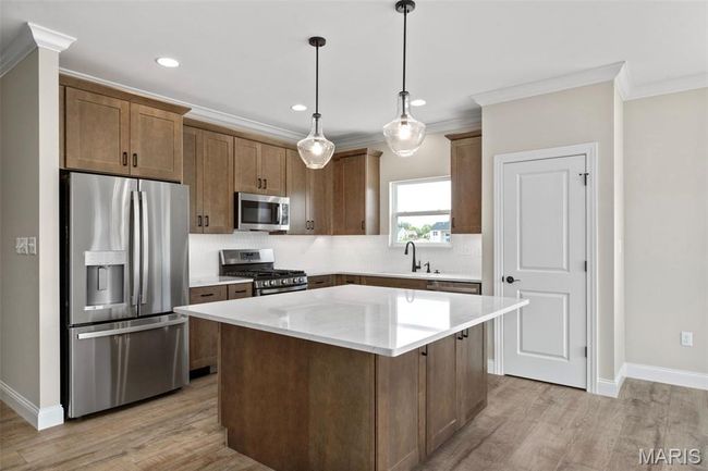 Kitchen with stainless steel appliances, crown molding, backsplash, light wood finished floors, and baseboards | Image 13