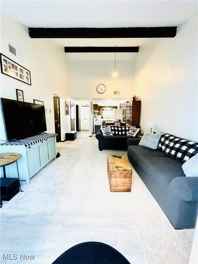 Living room with beamed ceiling, a high ceiling, and light colored carpet | Image 3