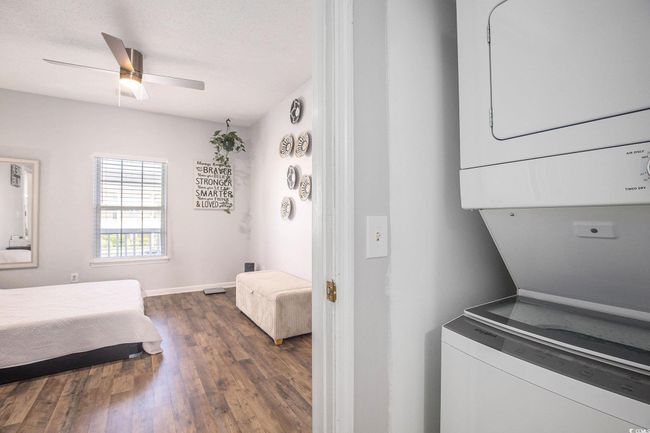 Laundry area featuring stacked washing machine and dryer, wood finished floors, and ceiling fan | Image 16