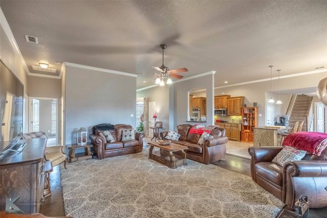 Living area with ceiling fan, ornamental molding, and a textured ceiling | Image 7